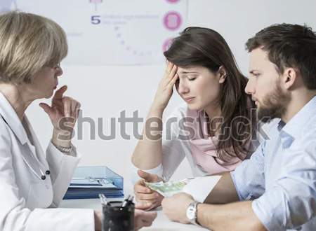 A therapist consults a distressed couple sitting across from her, with the woman holding her forehead and the man looking concerned, symbolizing a difficult discussion