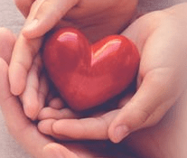 Hands gently cradling a small red heart, symbolizing love, care, and compassion