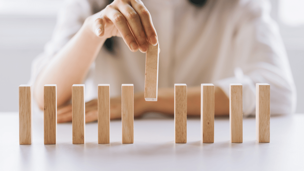 This image shows a person placing a wooden block among a row of blocks, representing the idea of building knowledge or understanding the complexities of hereditary depression.