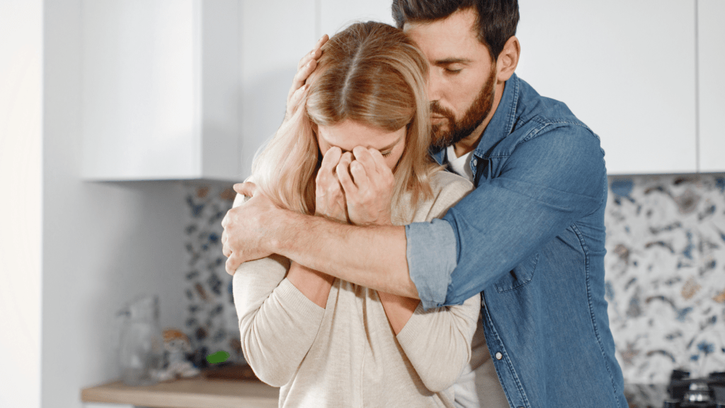  man hugging a crying woman, offering comfort, symbolizing support during depressive episodes, understanding hereditary depression, and seeking help.