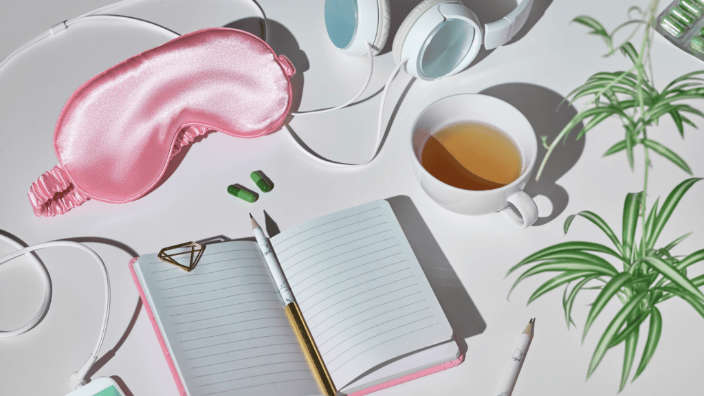 A collection of sleep essentials including a pink eye mask, tea, and a journal, representing the importance of a healthy sleep environment in combating fatigue. Why Does Depression Make You Tired?