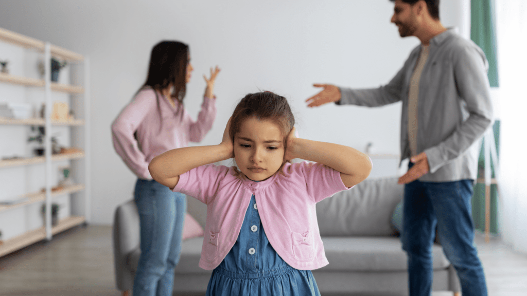 A young girl covering her ears while parents argue in the background, illustrating childhood trauma, negative self-image, and mental health impact.